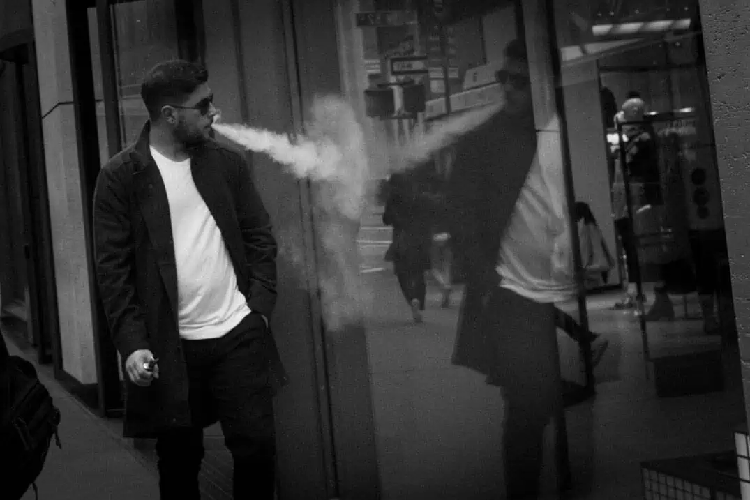 Man vaping and looking at his reflection, New York street photography