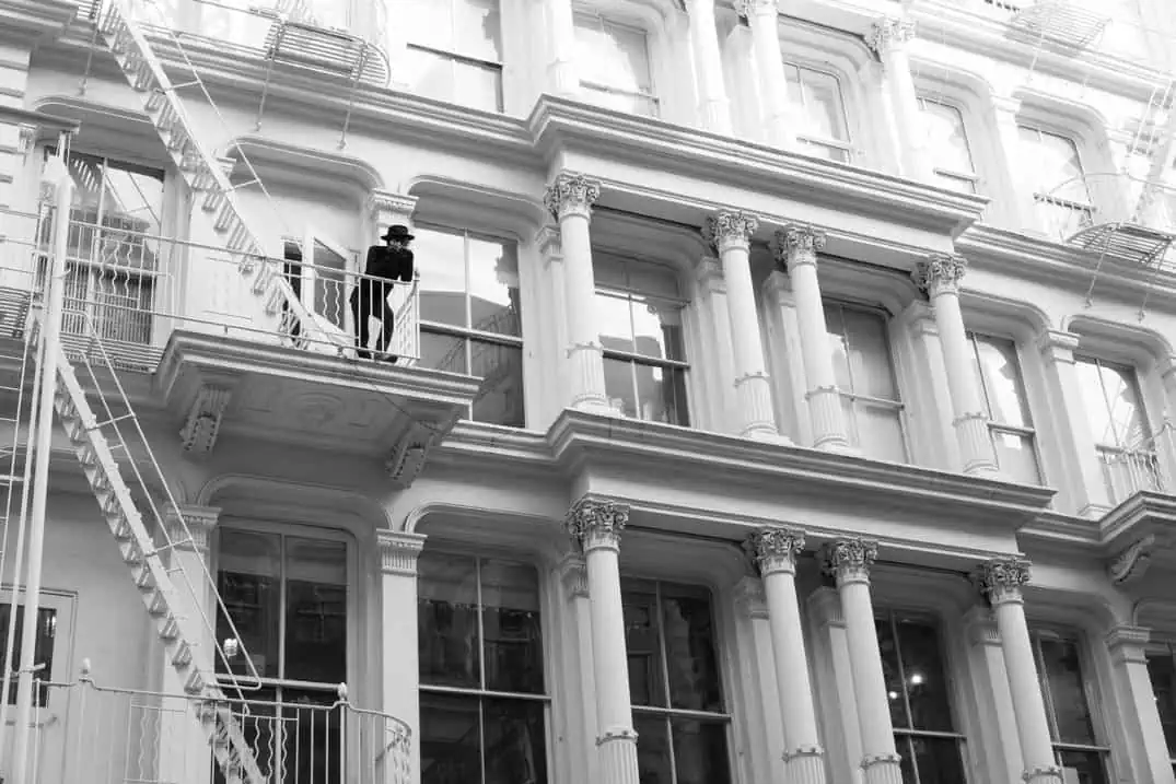 Man on a fire escape of a cast-iron building in SoHo, New York